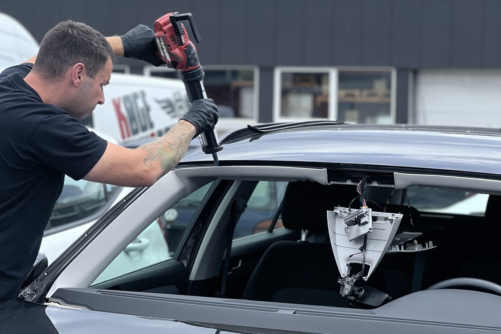 RUDEFIX-tekniker lægger limstreng på karmen ved udskiftning af forrude — beslaget til bilens ADAS-kamera er synligt i den tomme rudeåbning