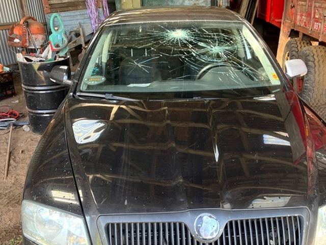 Sort Skoda med smadret forrude, parkeret i en lade